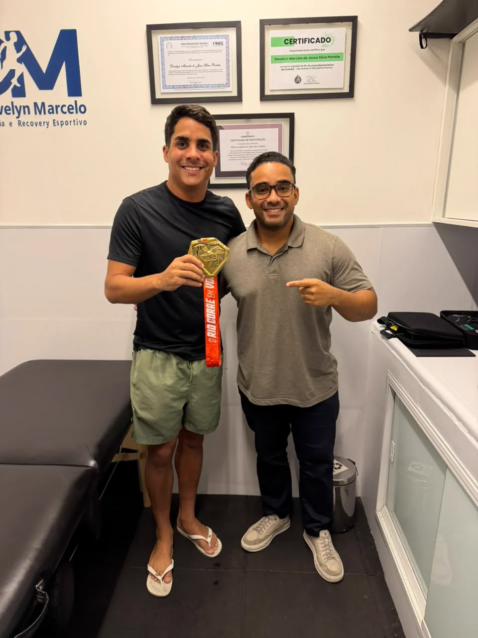 Dr. Develyn e paciente com medalha na sala de atendimento do consultório