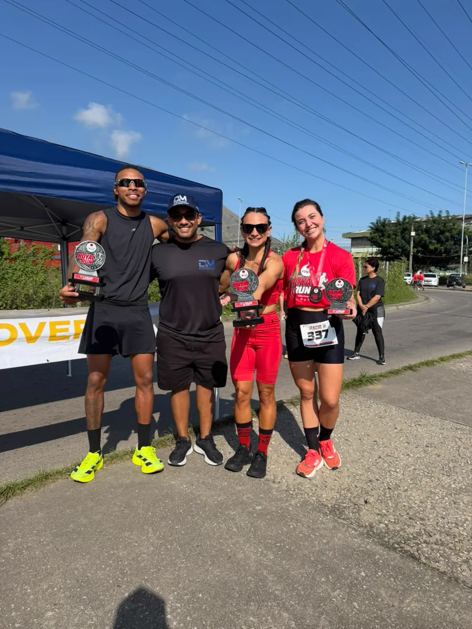 Dr. Develyn ao lado de atletas campeões segurando os troféus de 1º lugar da Royal Run